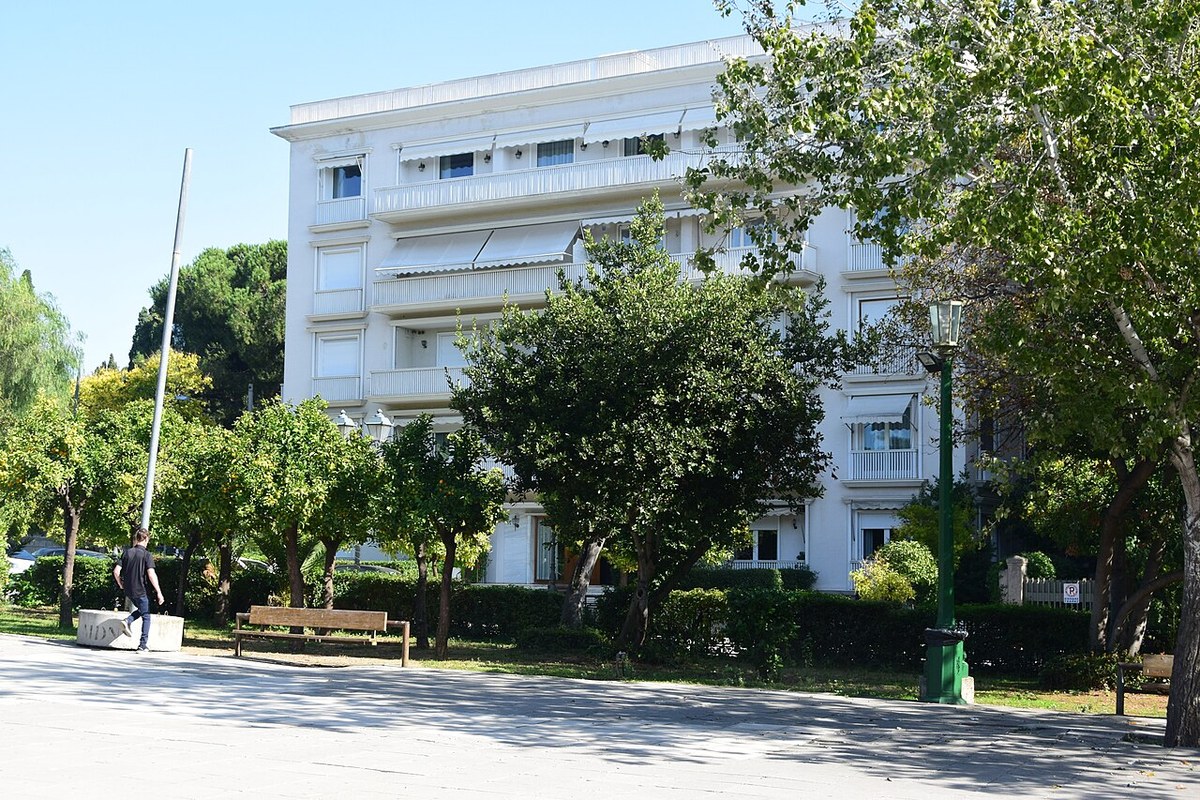 Yunanistan'da ev almak: baştan sona süreç 10 Atina'da portakal ağaçlarının önünde bakımlı beyaz apartman cephesi